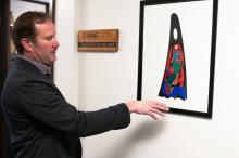 Chris Teuton, chair of American Indian Studies, shows off original artwork by local artist and AIS professor emeritus, Marvin Oliver, in the AIS office