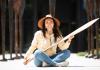 Stephanie Masterman sits outside the Burke museum holding a Tlingit cedar canoe paddle she recently carved